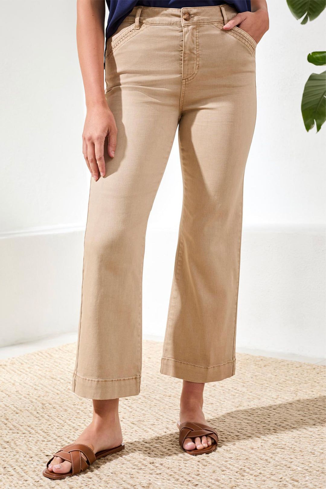 Person wearing beige pants standing on a textured surface with a white wall in the background