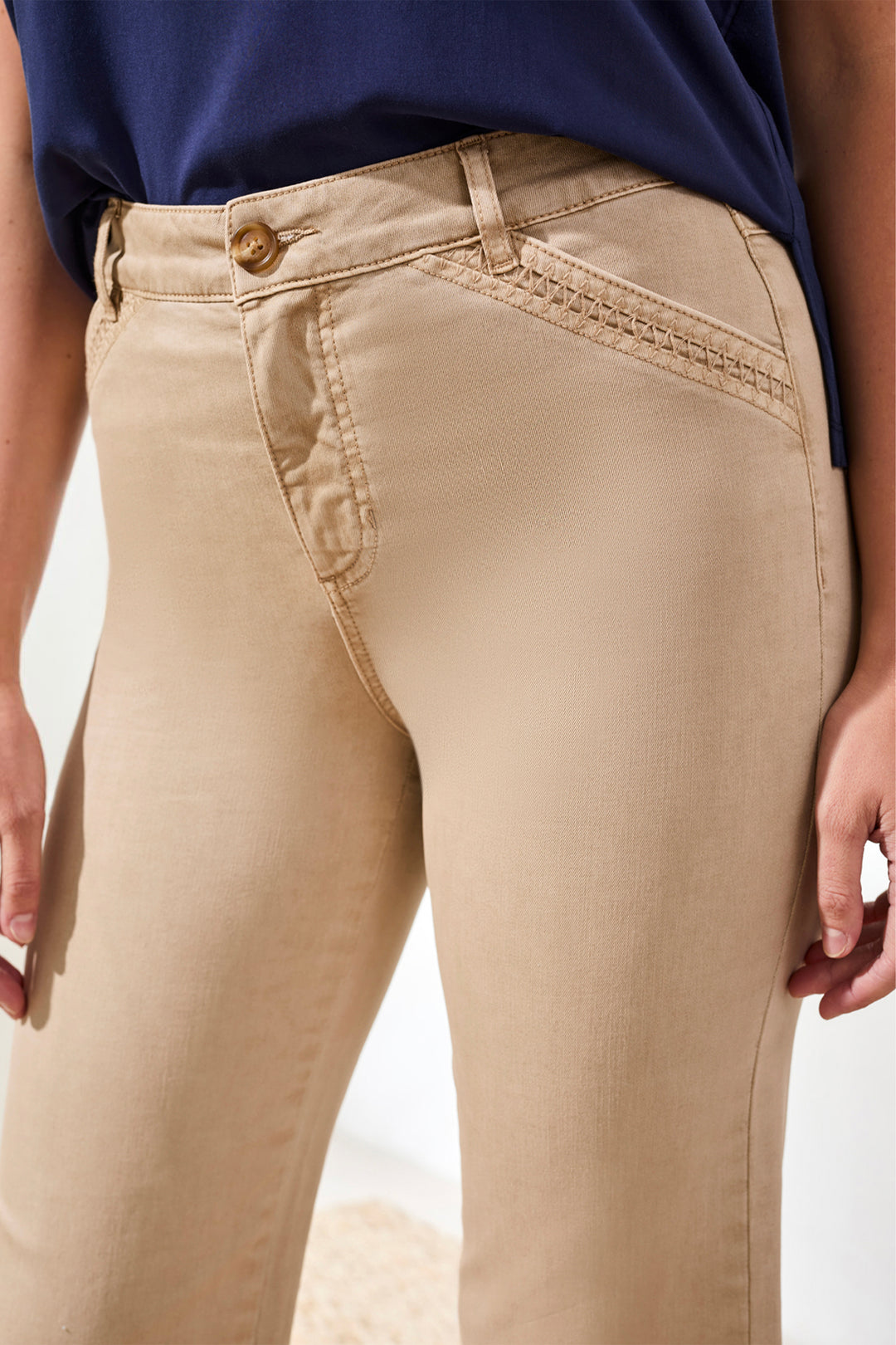 Beige pants worn by a person on a white background