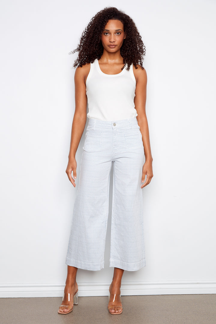 Woman wearing a white sleeveless top and light gray wide-leg pants against a white background