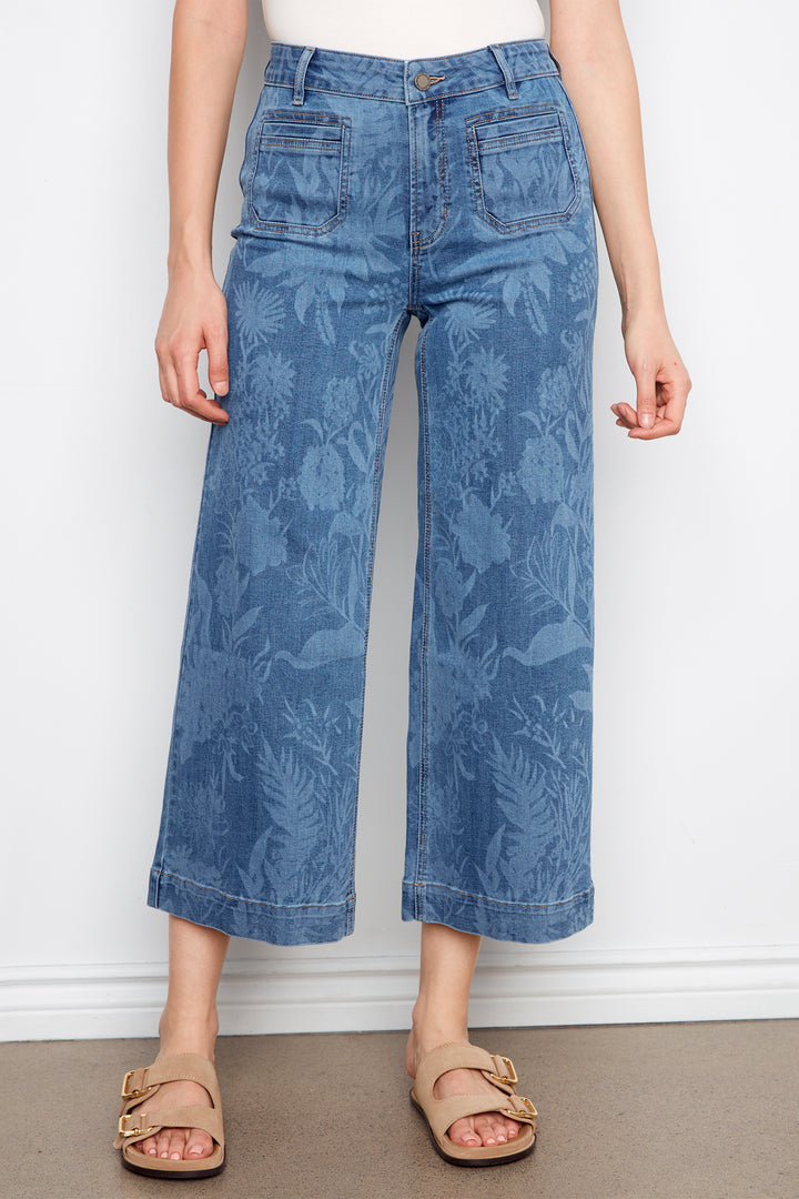 Person wearing blue patterned jeans against a white background