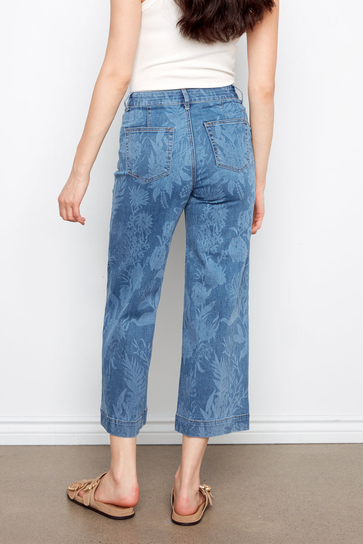 Person wearing blue floral jeans against a white background