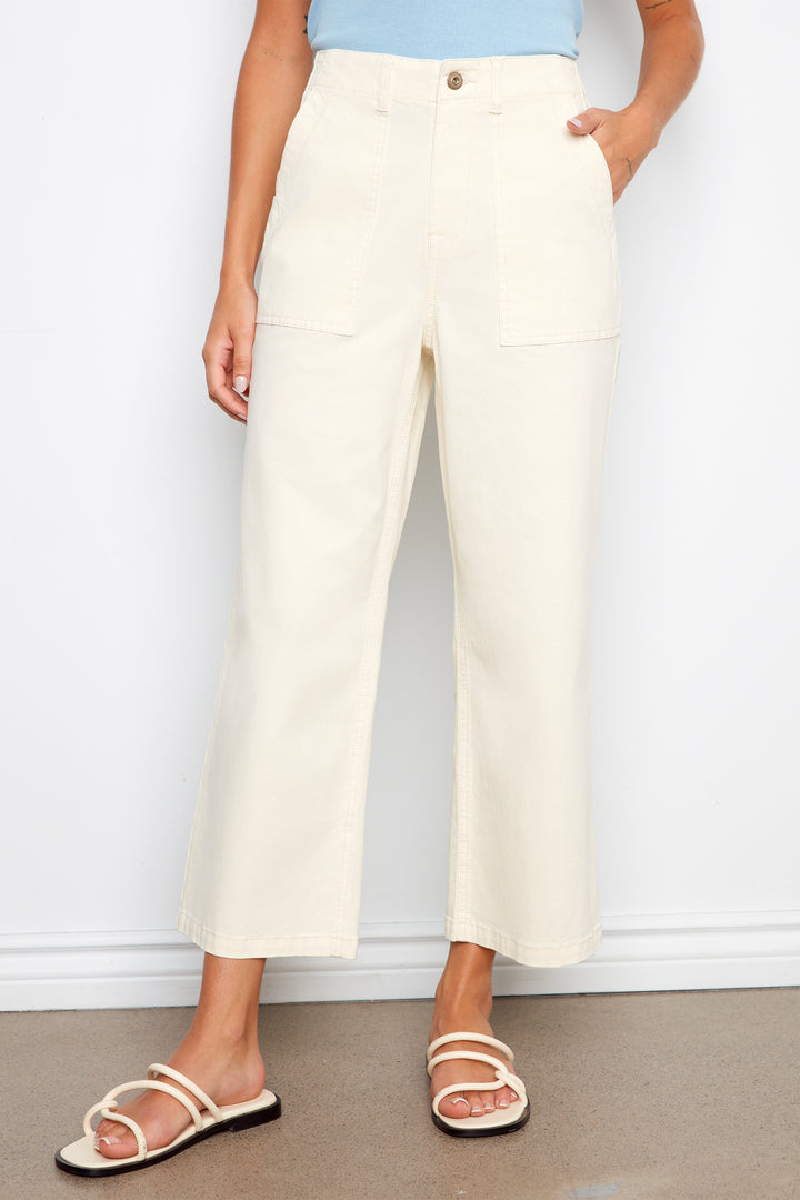 Person wearing white pants and sandals against a plain background