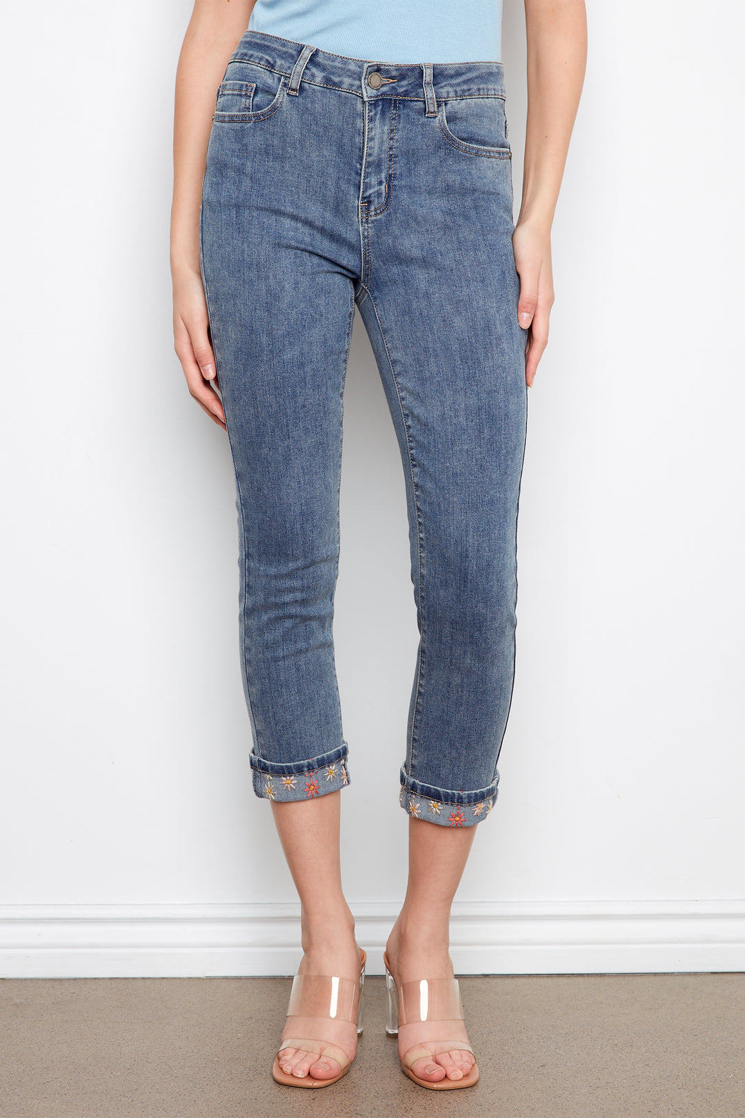 Person wearing blue jeans with a white wall background