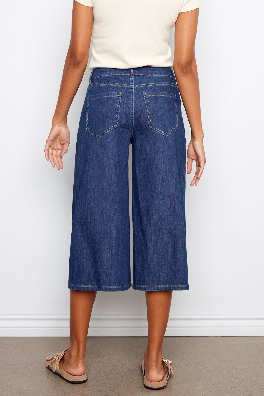 Person wearing blue denim culottes against a white background