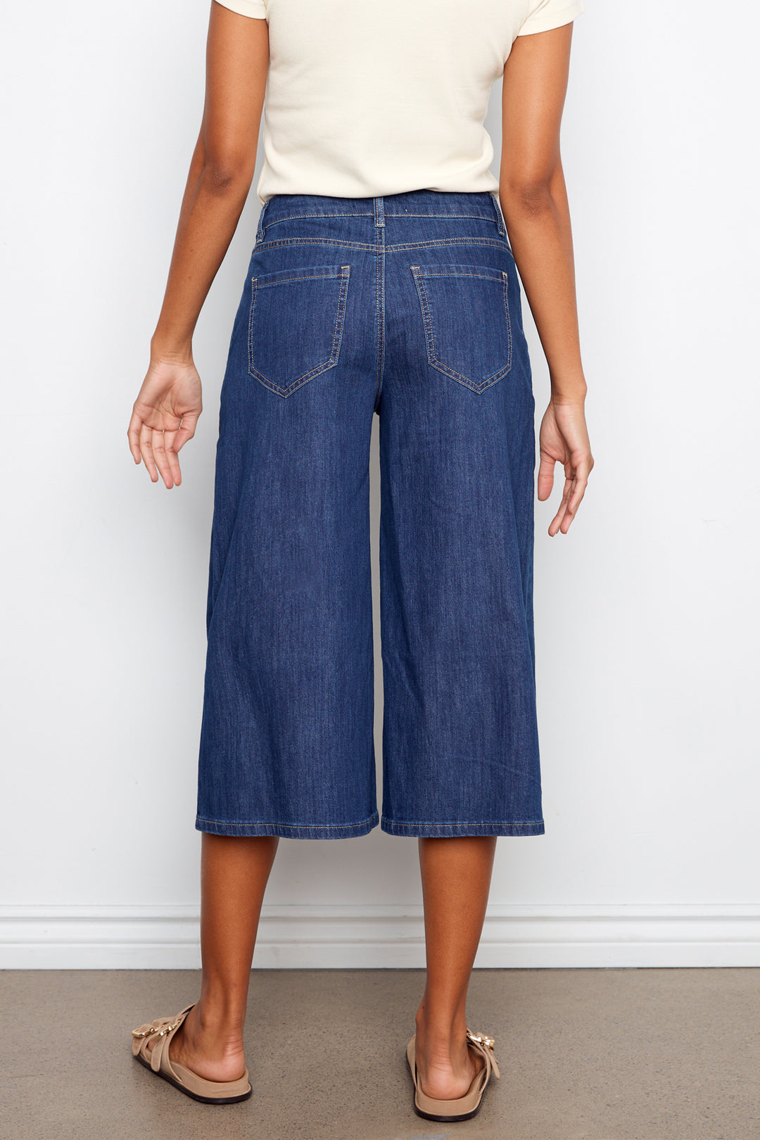 Person wearing blue denim culottes against a white background