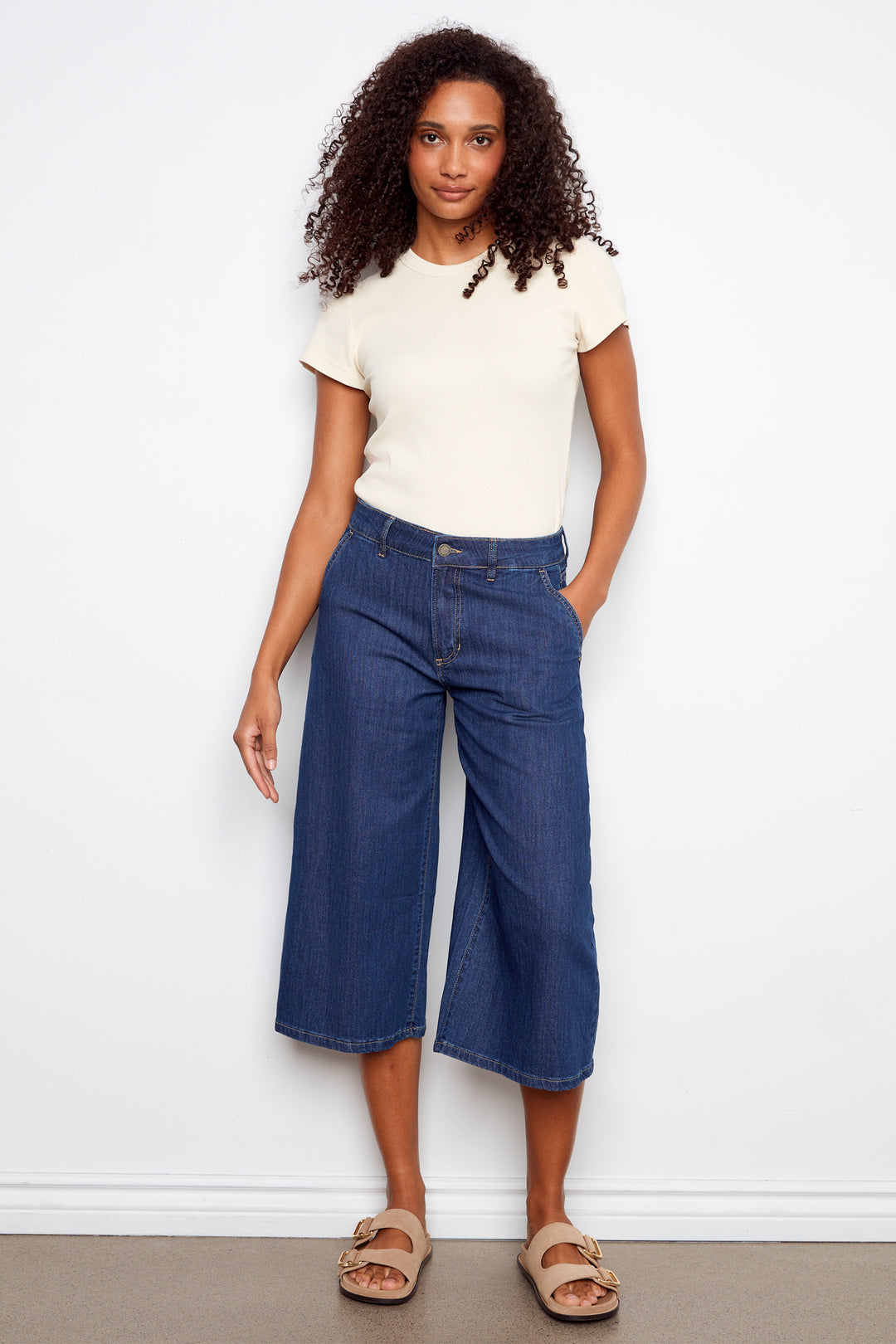 Woman wearing a white t-shirt and blue jeans against a white background