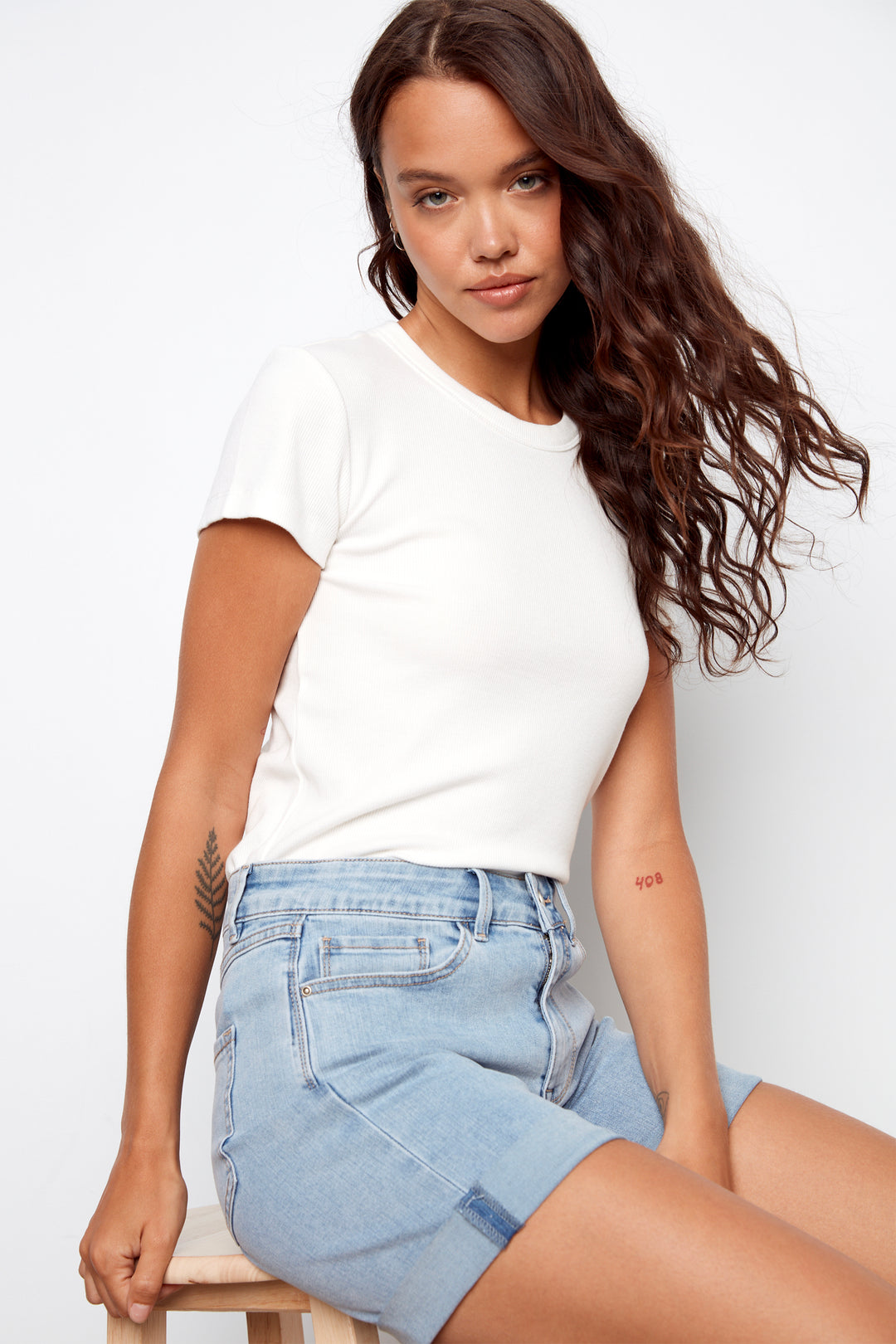Woman wearing a white t-shirt and light blue denim shorts on a white background
