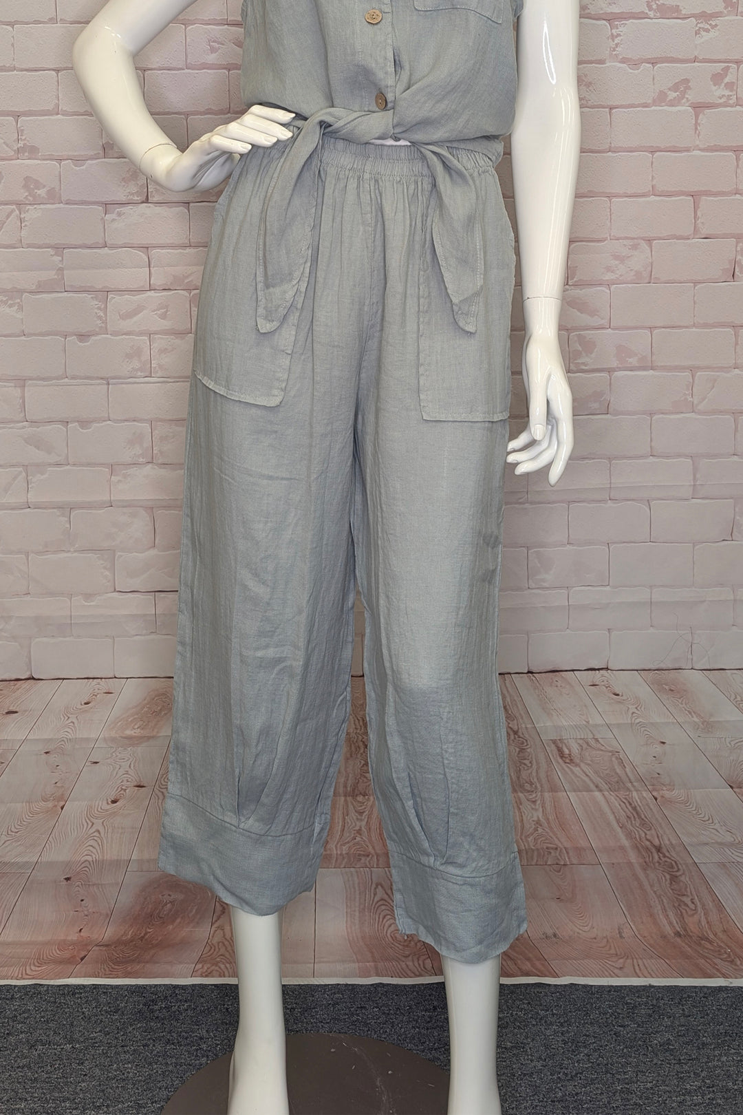 Mannequin wearing gray linen joggers against a brick wall.