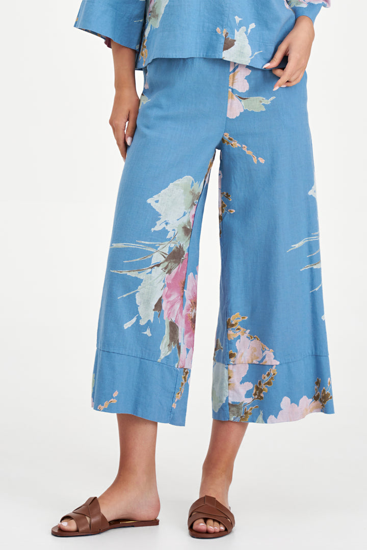 Person wearing blue floral pants with a matching top on a white background