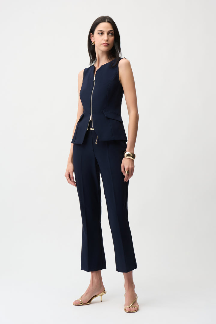 Woman wearing a navy blue sleeveless blazer and pants on a white background