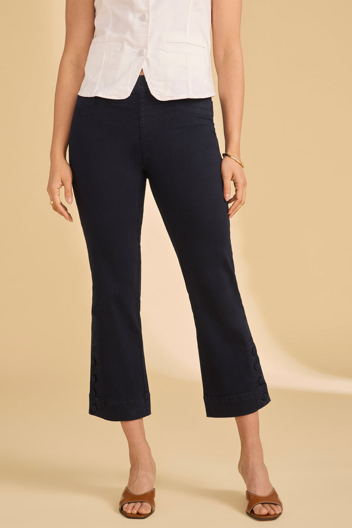 Person wearing navy blue crop jeans and a white top on a beige background