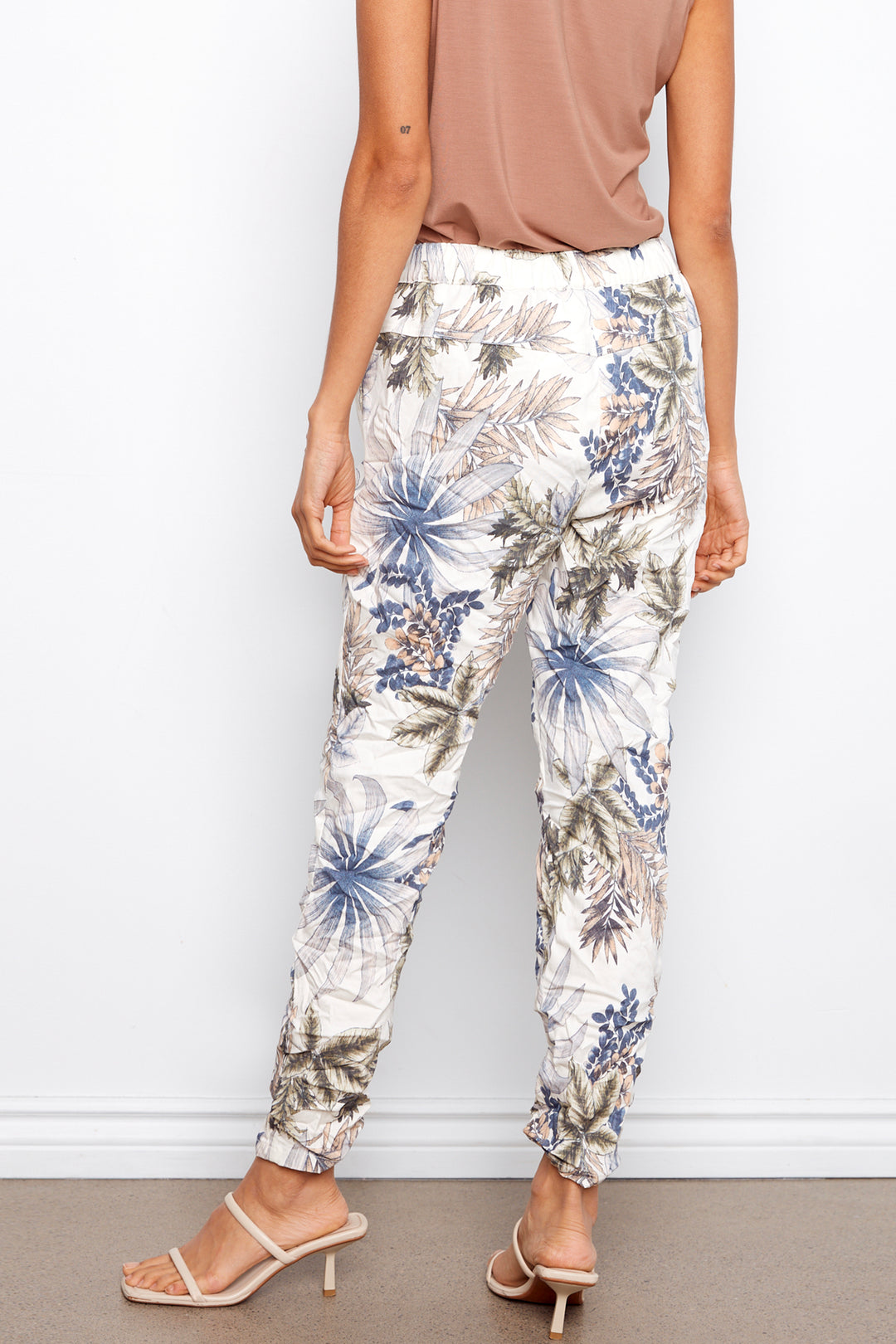 Floral pants worn by a person against a white wall