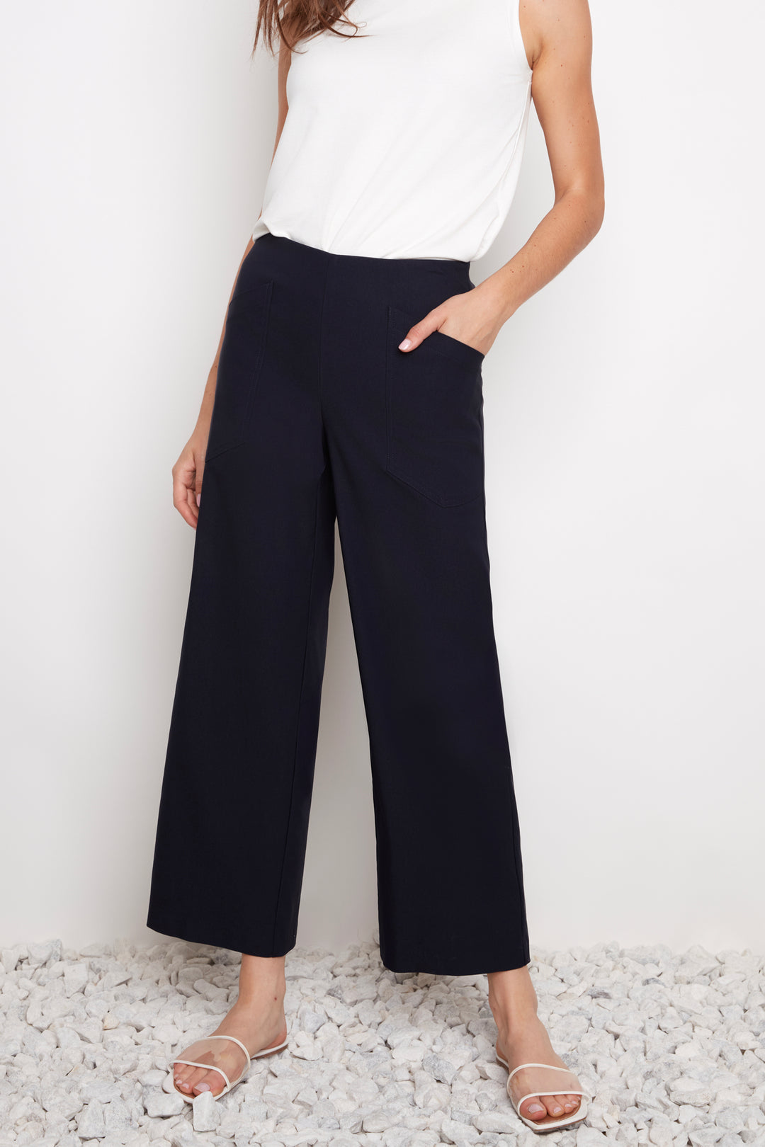 Person wearing navy wide-leg pants and a white top on a light background