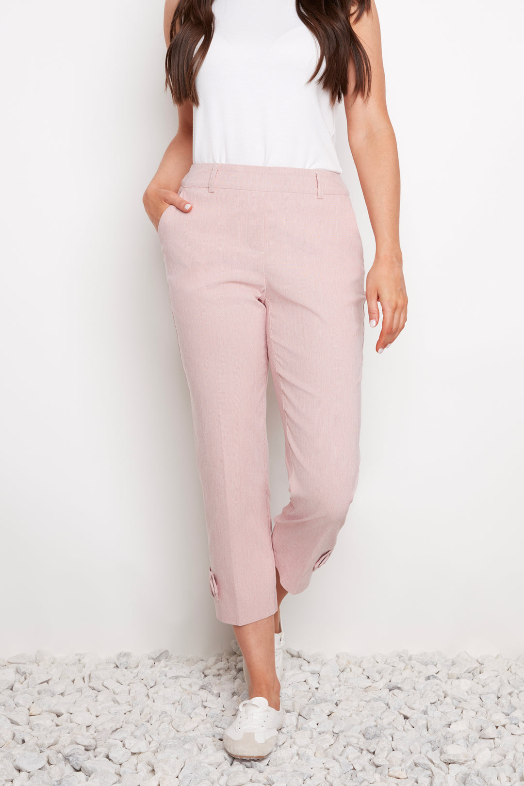 Person wearing light pink pants and a white top on a white background