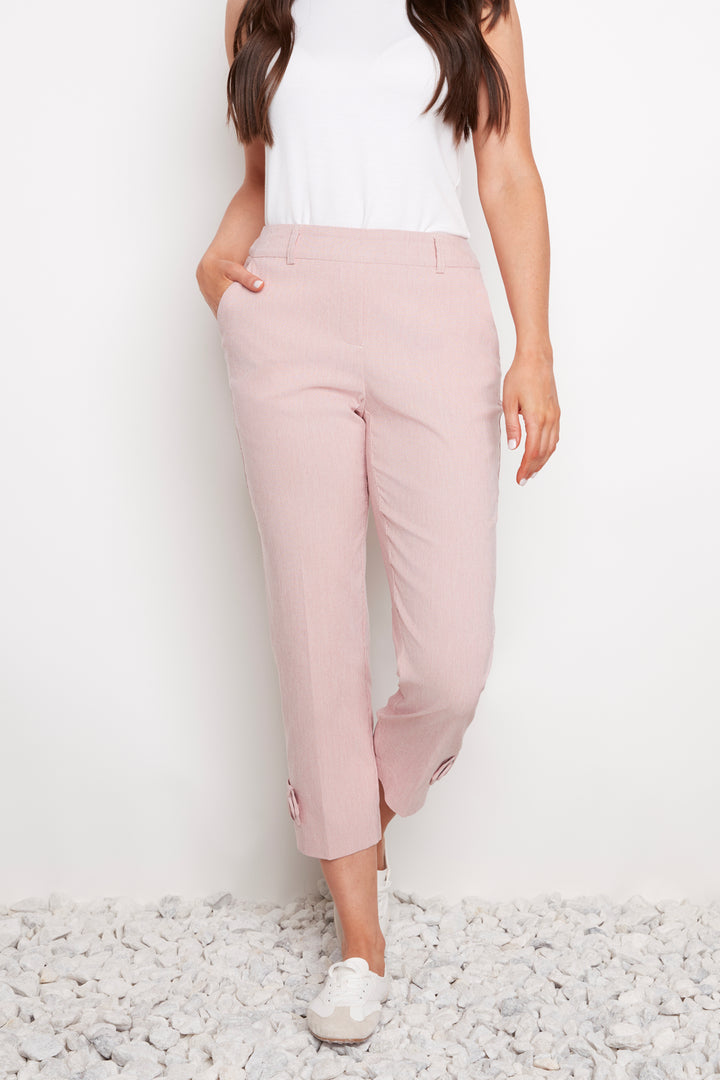 Person wearing light pink pants and a white top on a white background