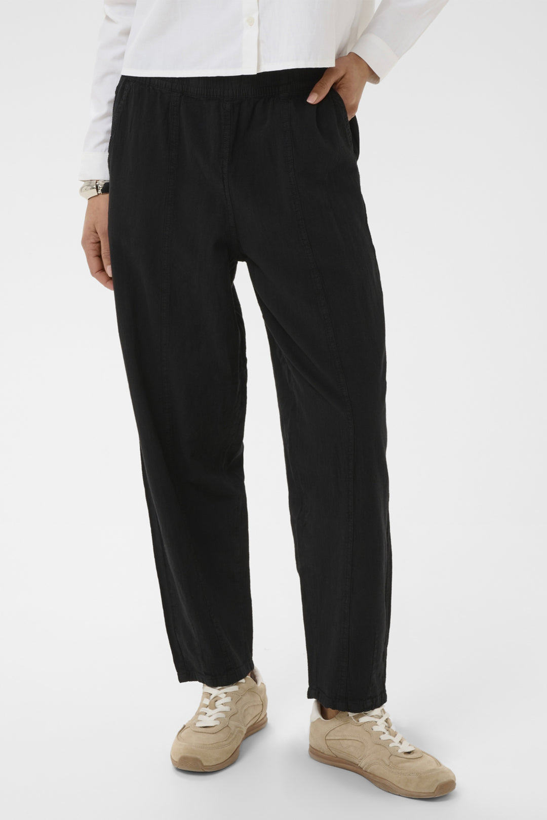 Person wearing black barrel leg pants and a white shirt on a white background