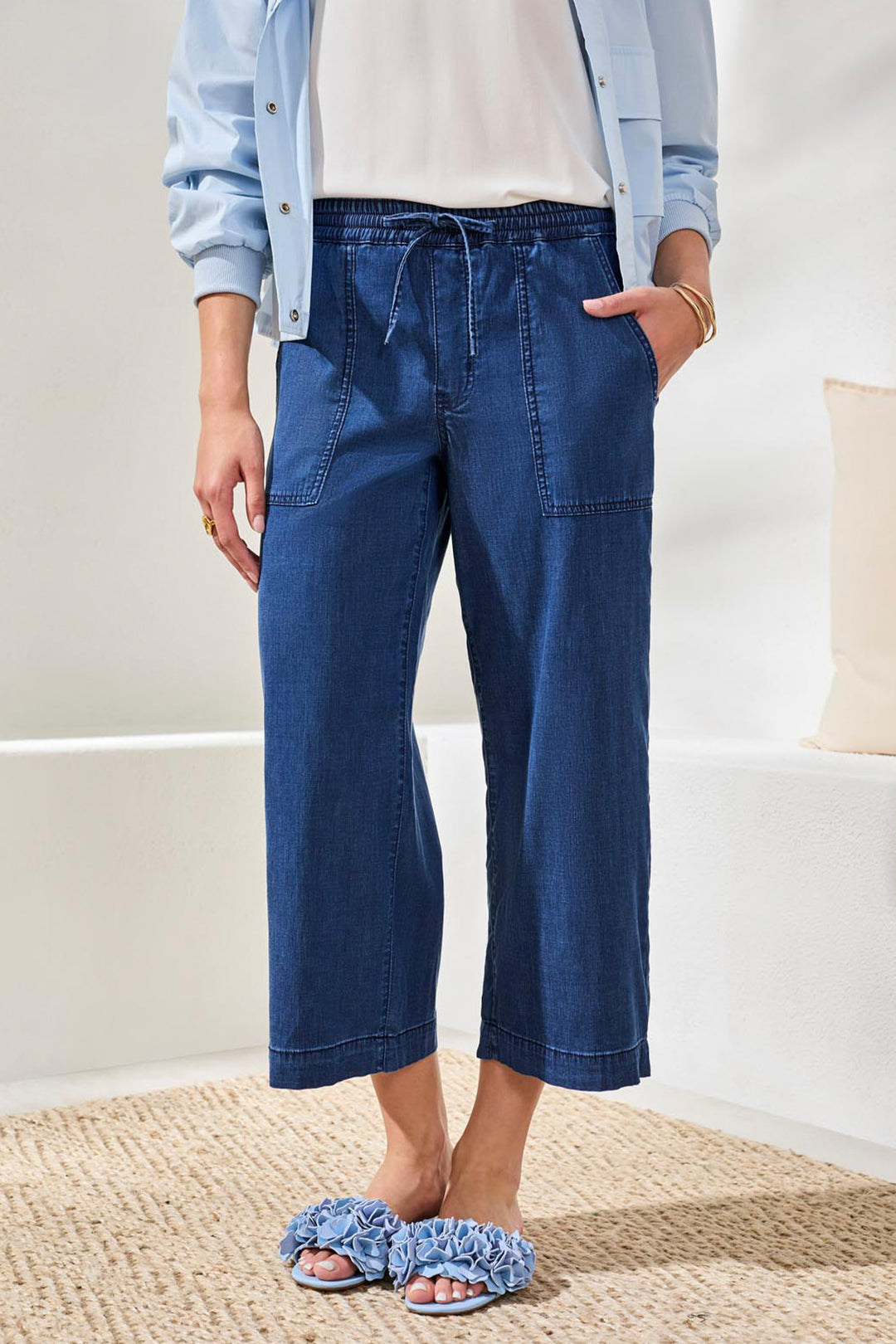 Person wearing blue capri jeans and a light blue shirt in a minimal indoor setting