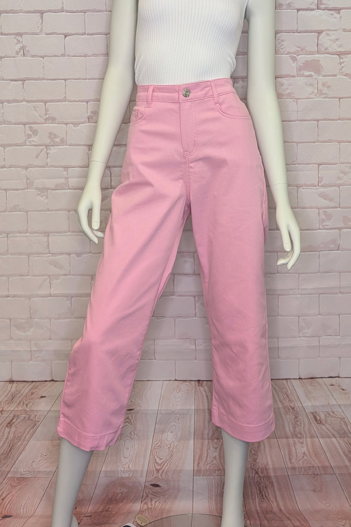 Mannequin wearing pink crop pants against a brick wall.
