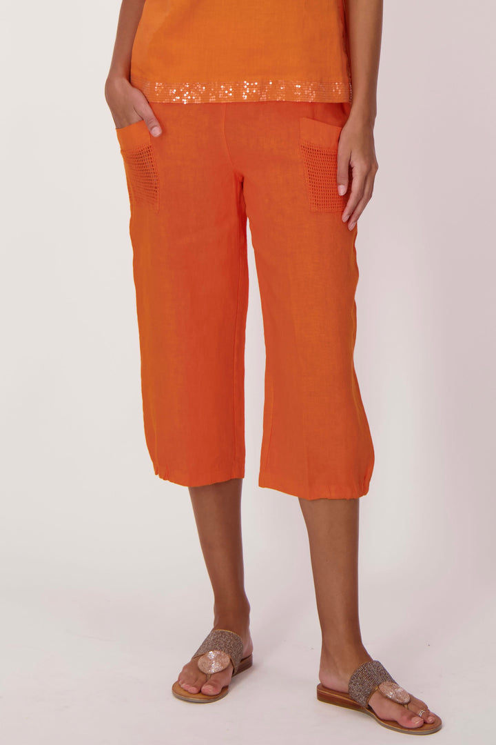 Person wearing orange capris and top on a white background