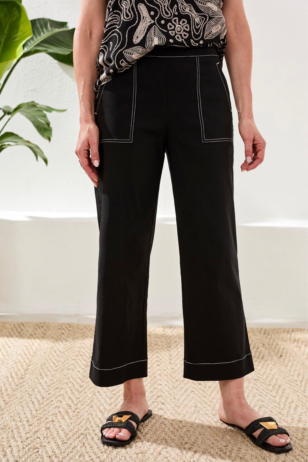 Person wearing black wide leg pants with white stitching indoors