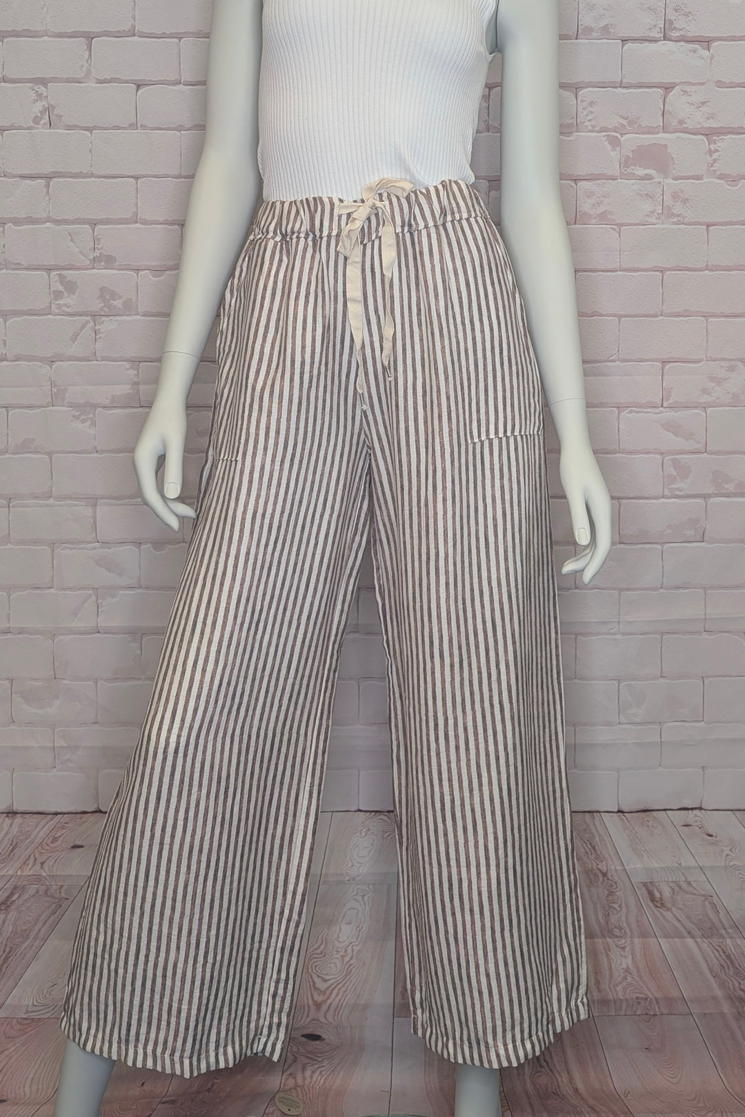 Mannequin wearing striped pants with drawstring against a brick wall background