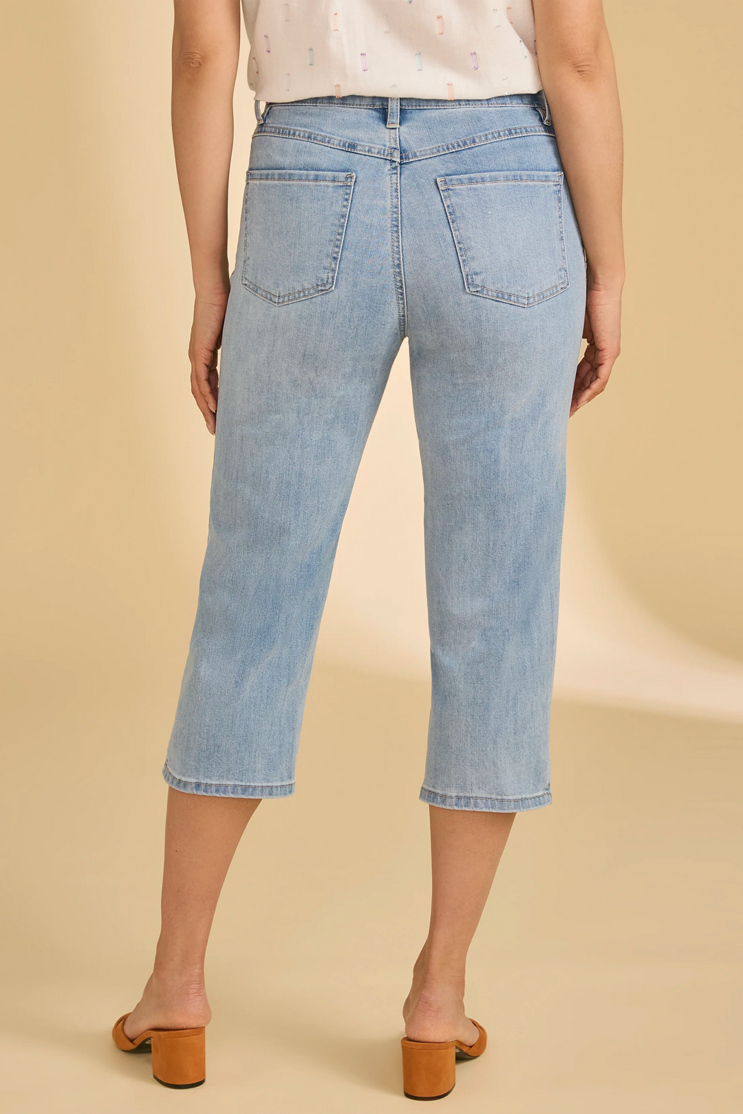 Light blue jeans worn by a person on a beige background