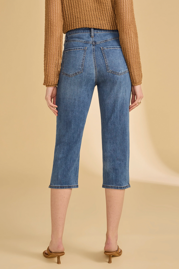 Person wearing blue jeans and a brown sweater on a beige background
