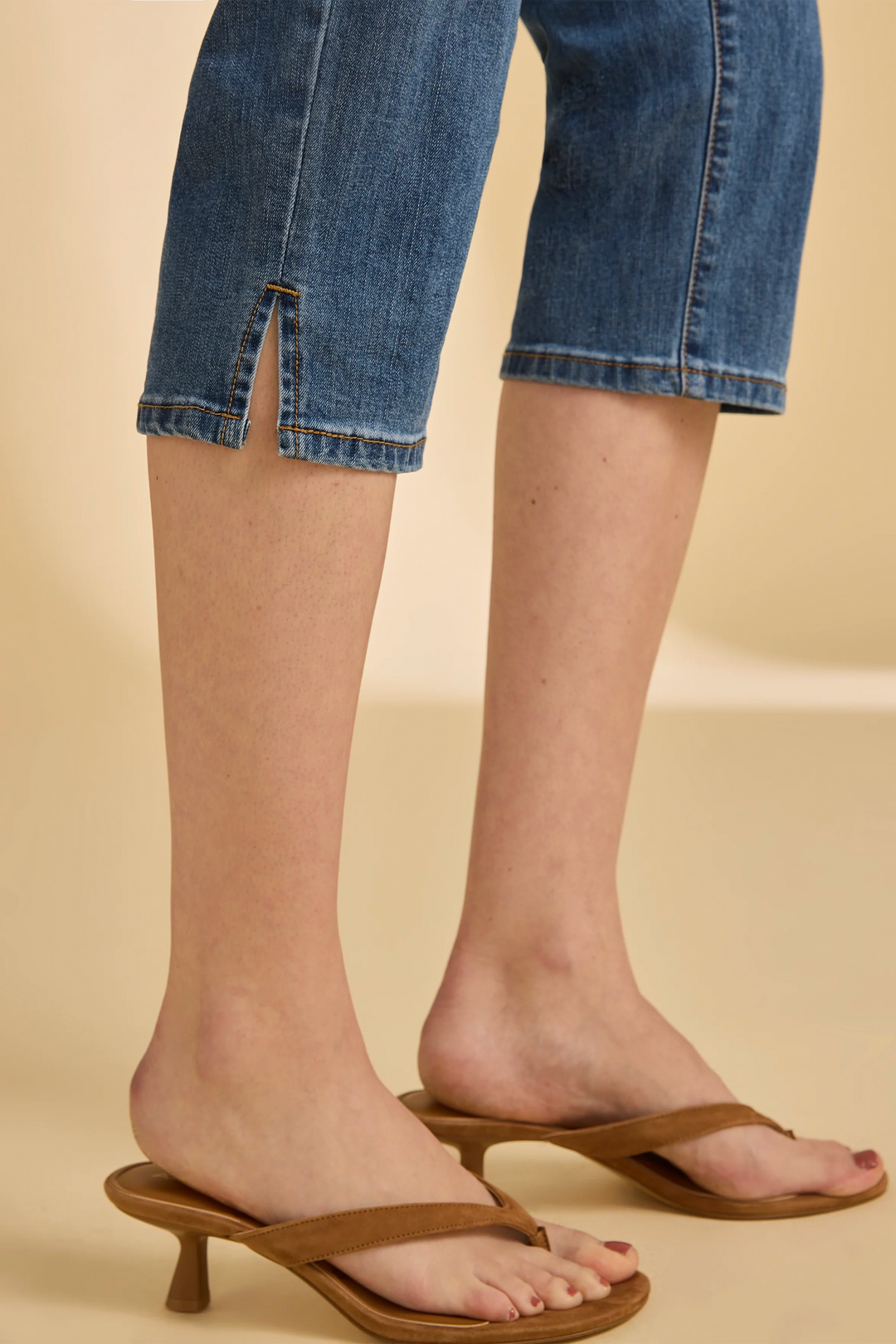 Brown sandals worn with blue jeans on a beige background