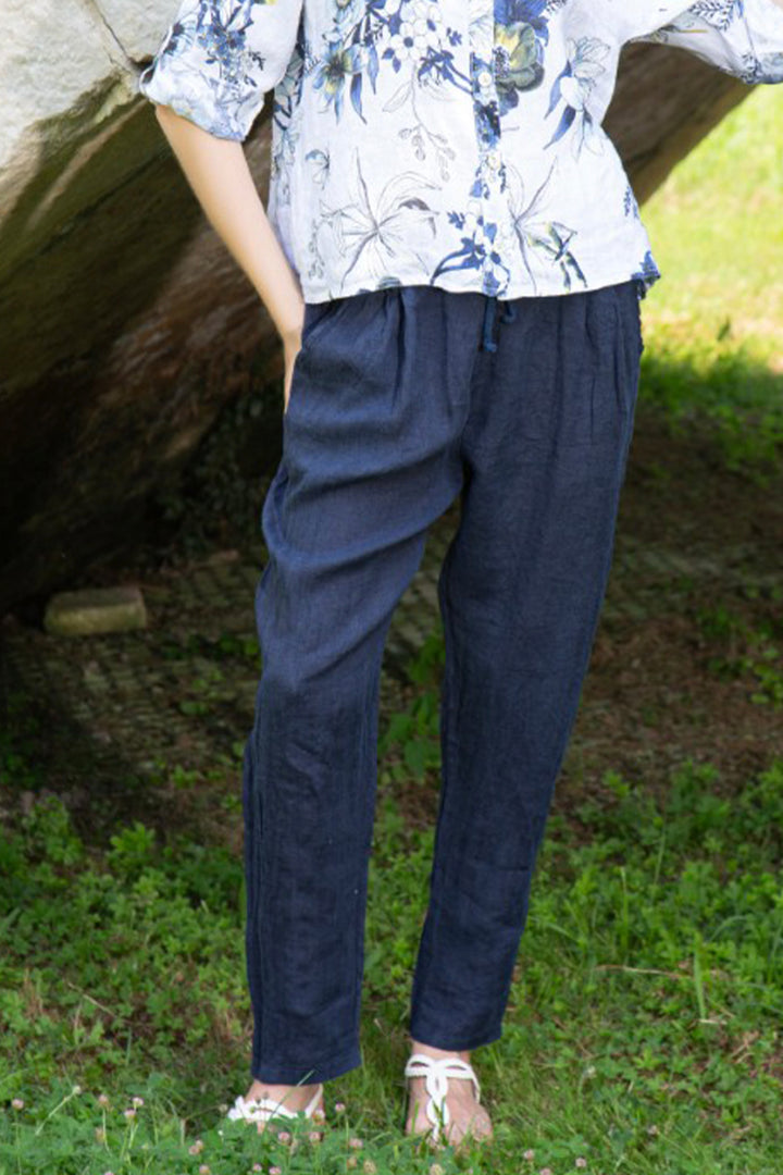 Person wearing a linen navy pant with drawstring standing in a natural setting.