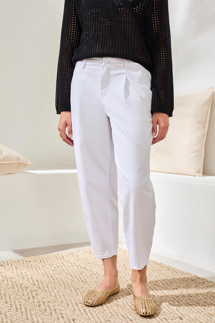 Person wearing white crop barrel jeans and a black top in a minimal indoor setting