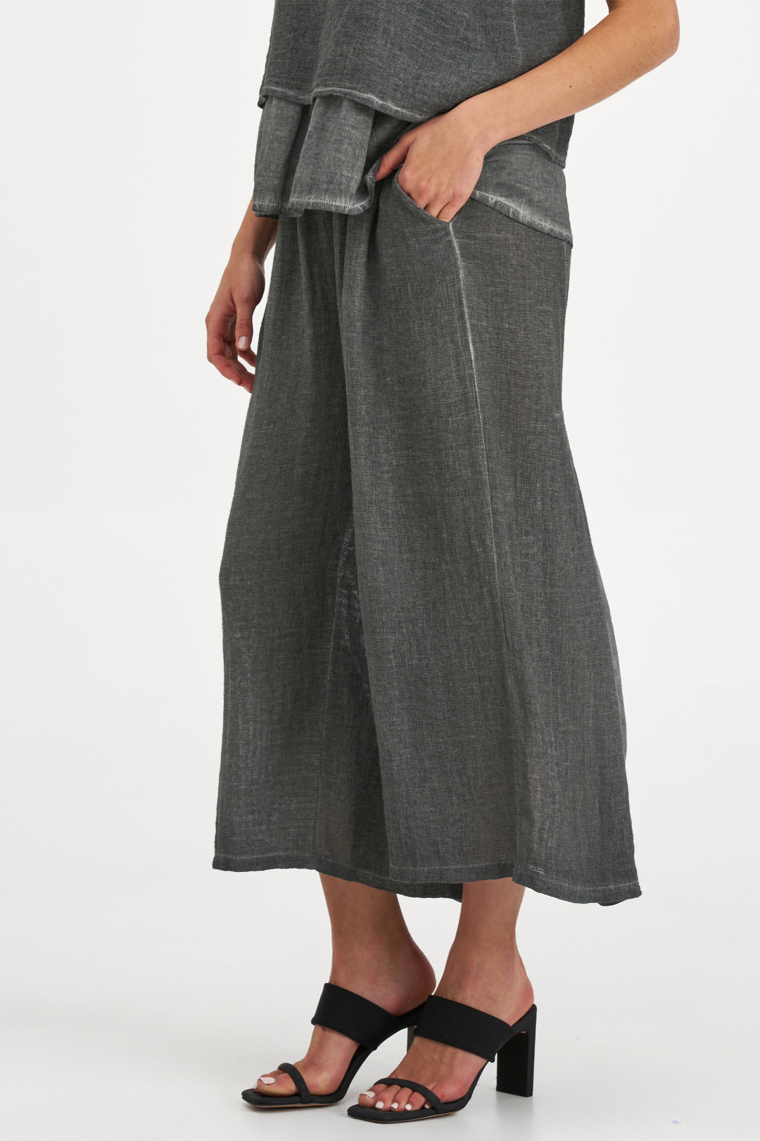 Person wearing a gray wide-leg crop pants on a white background