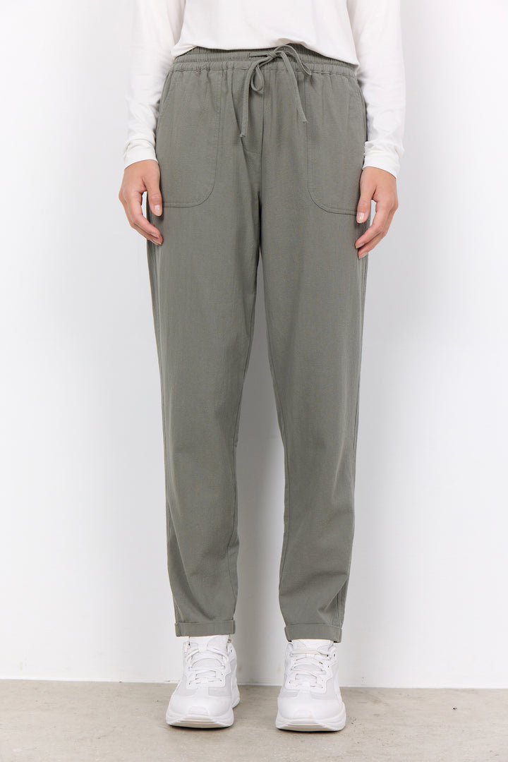 Person wearing gray jogger pants and white sneakers on a plain background