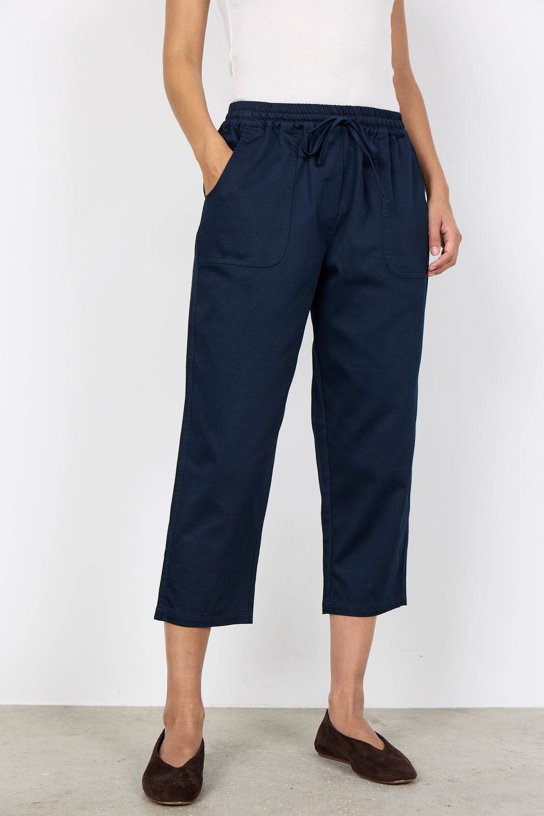 Person wearing navy blue crop pants with a white background