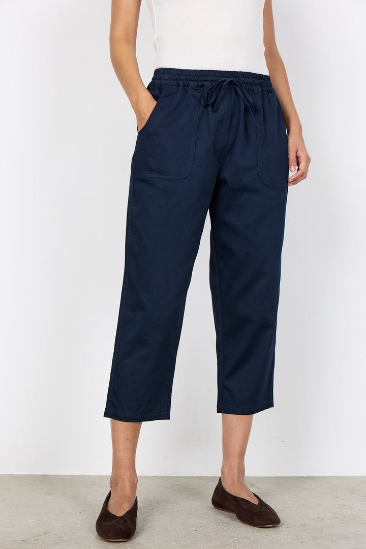 Person wearing navy blue crop pants with a white background