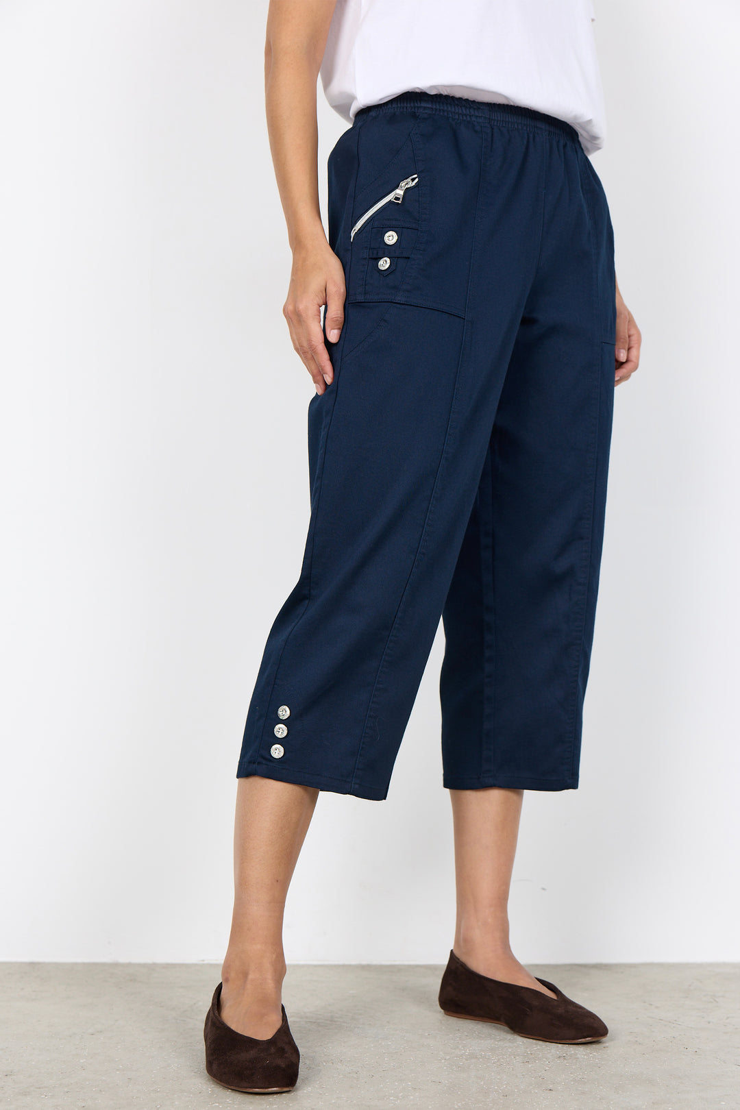 Navy blue capris with button details worn by a person on a white background