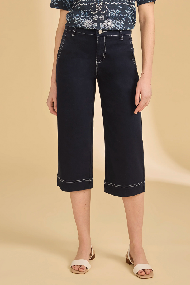 Person wearing black wide-leg capris on a beige background