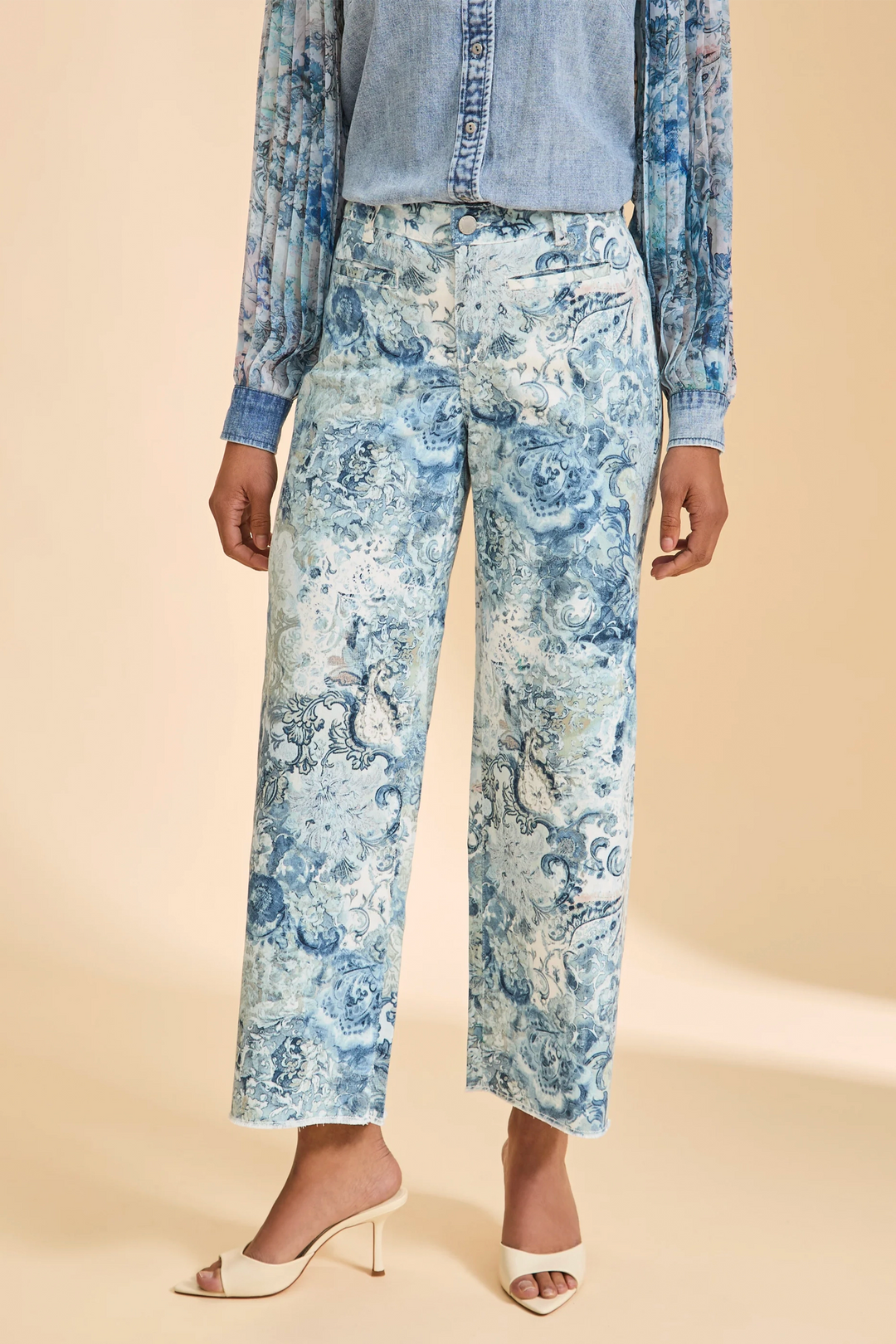 Person wearing blue floral wide leg pants and a denim jacket on a beige background