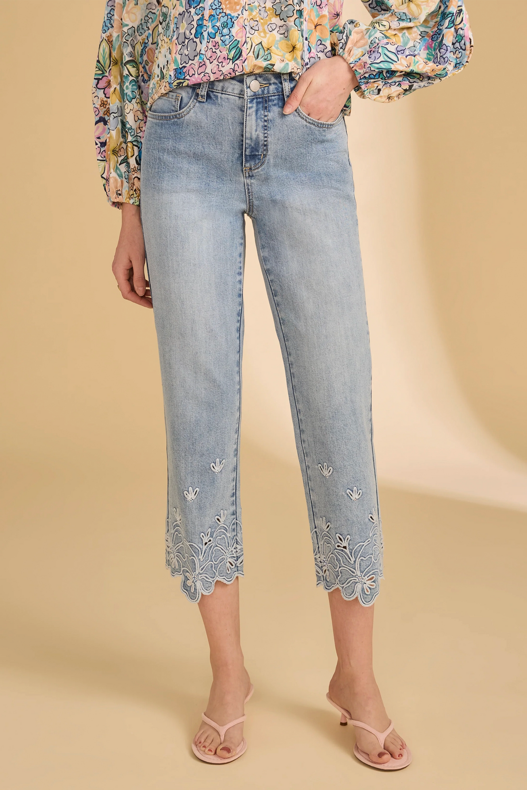 Light blue crop jeans with floral embroidery on a beige background