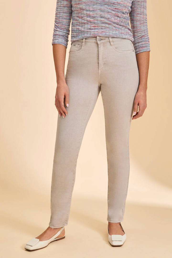 Person wearing beige slim leg jeans and a patterned top on a beige background