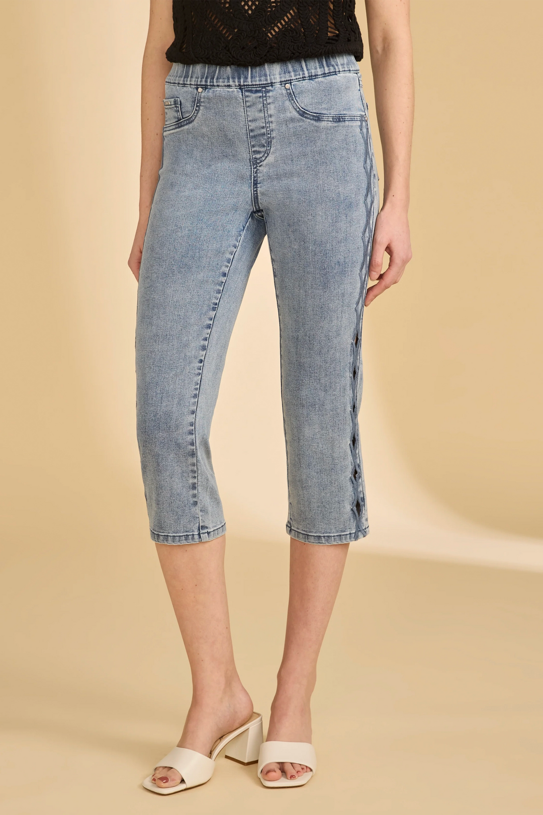 Person wearing light blue denim capri pull-on pants on a beige background