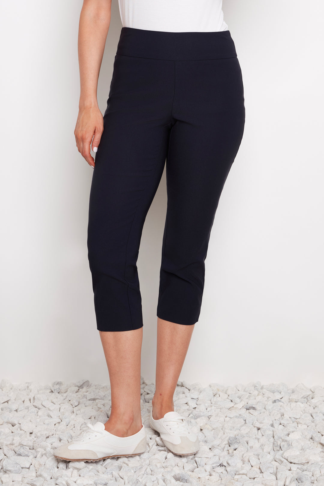 Person wearing navy capri pants on a white background