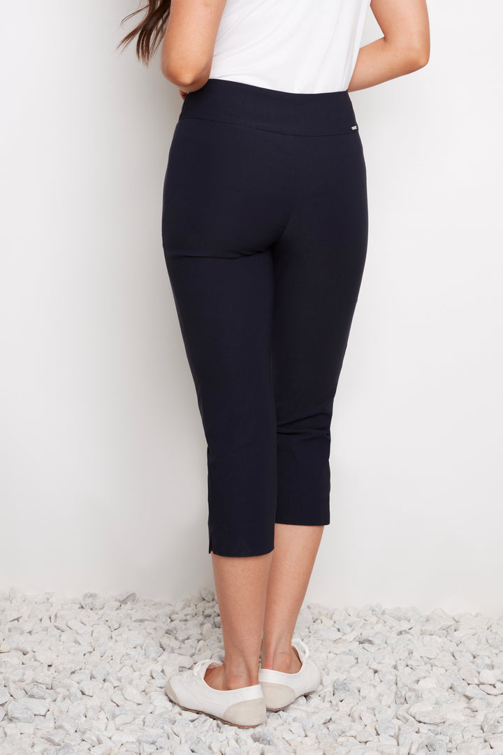 Person wearing navy capri pants and white shoes on a light gray background