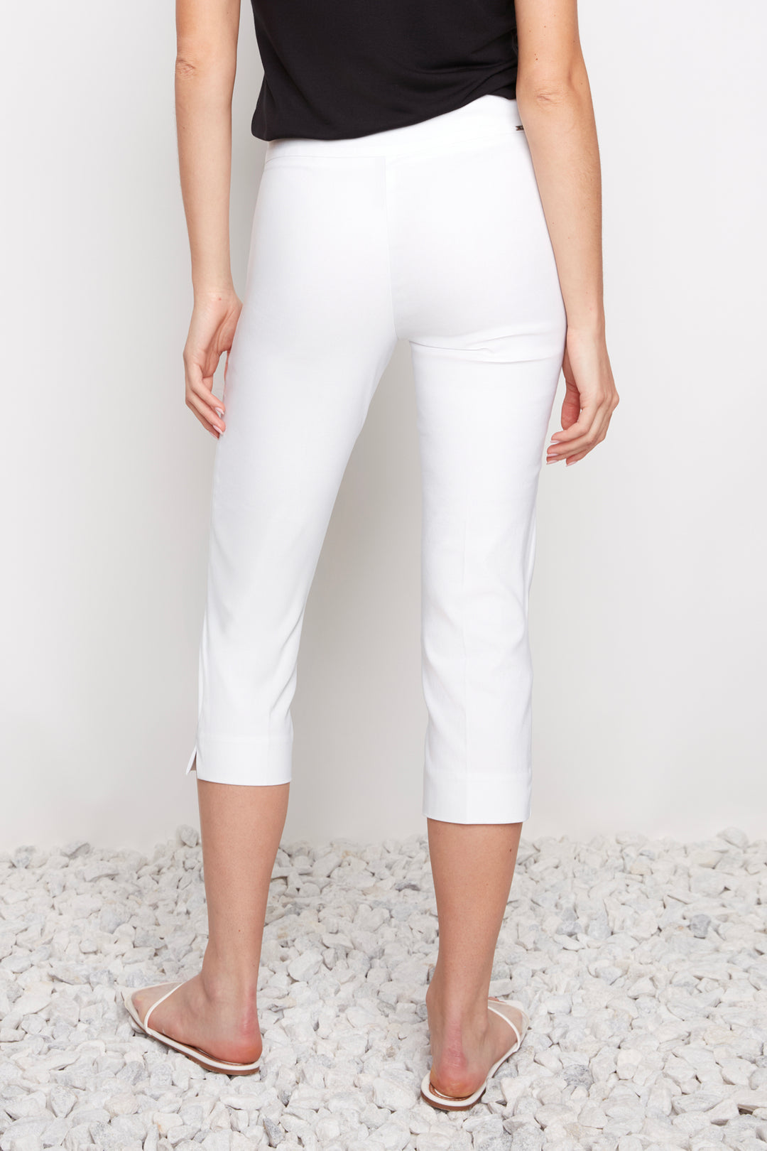 Person wearing white capri pants on a light background
