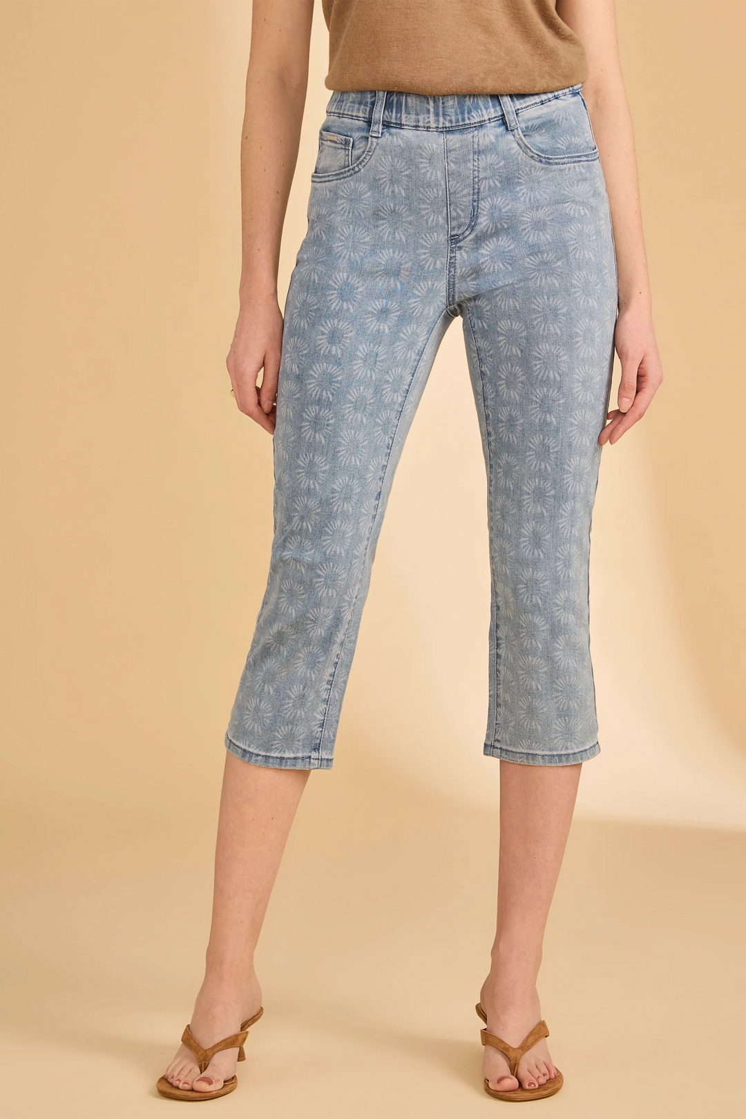 Person wearing light blue denim capri pants on a beige background