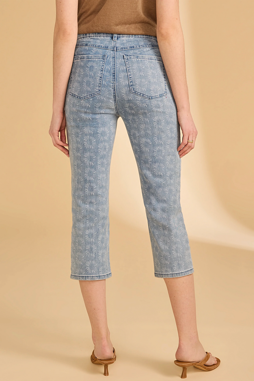 Person wearing light blue floral-patterned jeans on a beige background