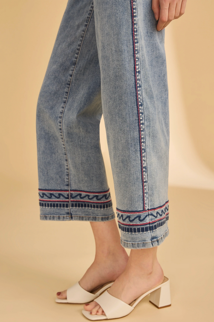 Denim pants with decorative hem on a beige background