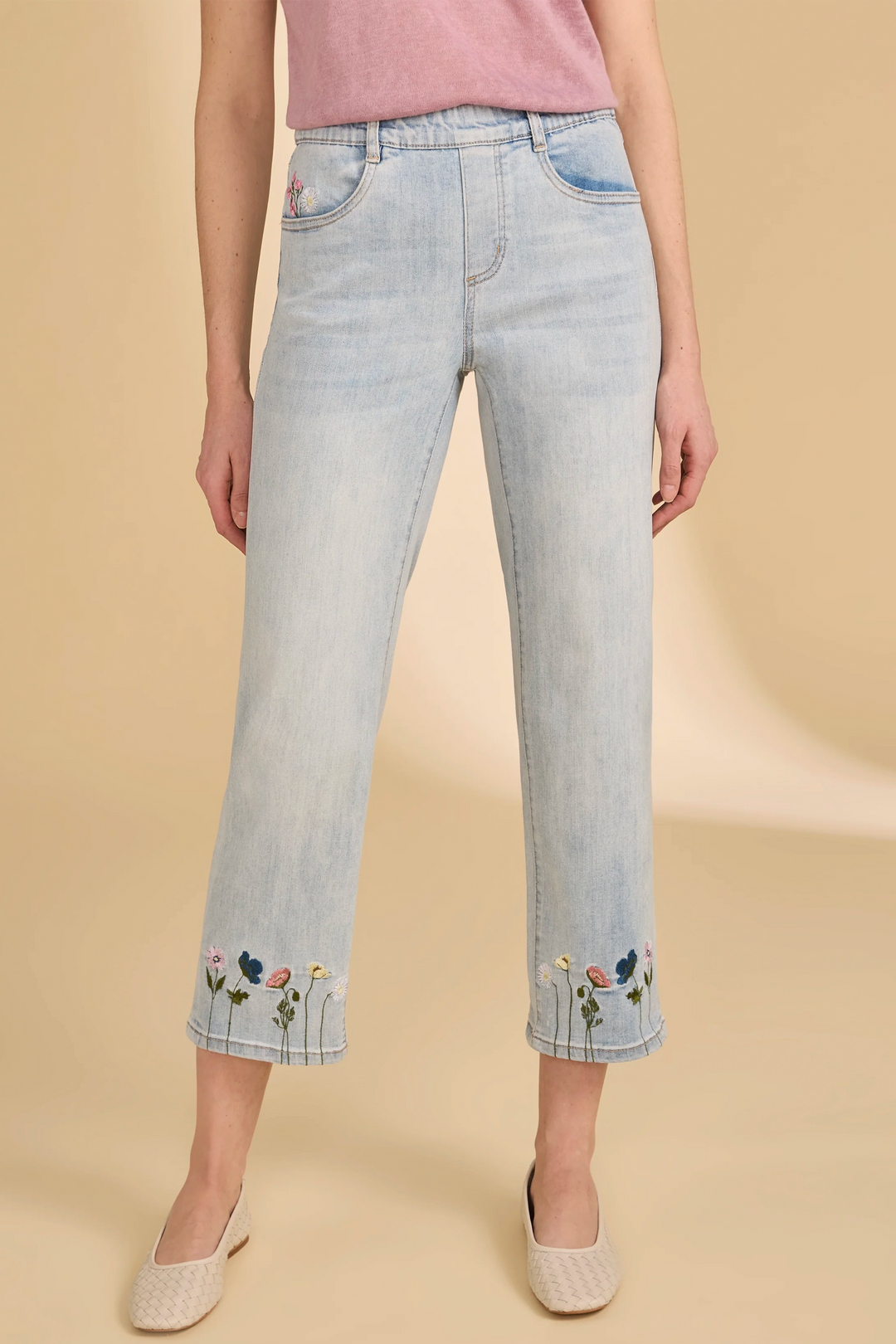 Light blue jeans with floral embroidery on a beige background