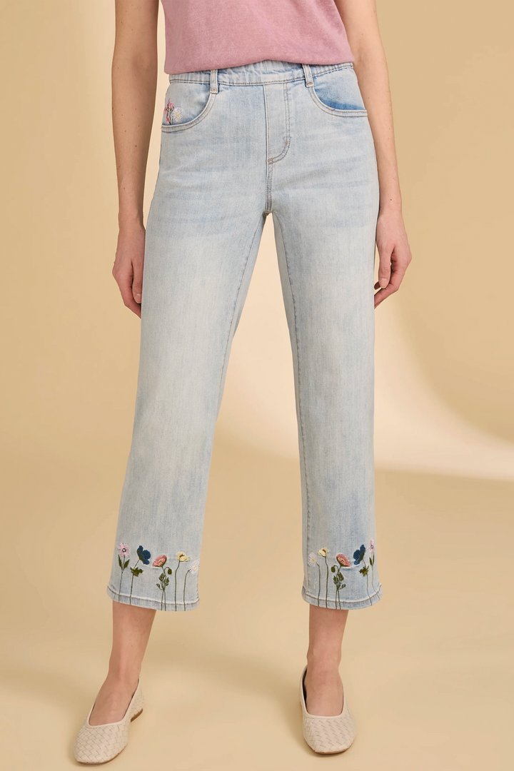 Light blue jeans with floral embroidery on a beige background