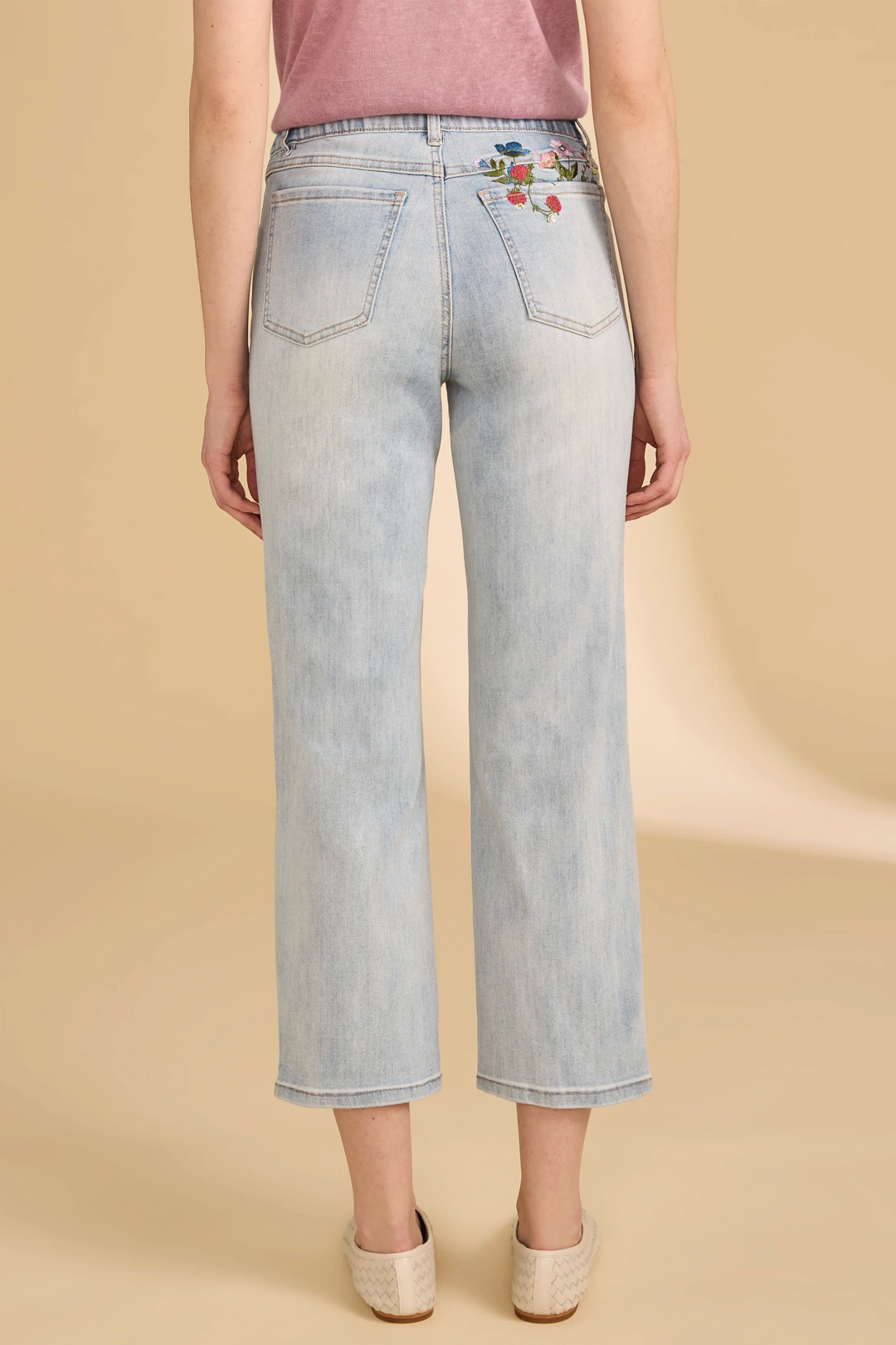 Light blue jeans with floral embroidery on a beige background