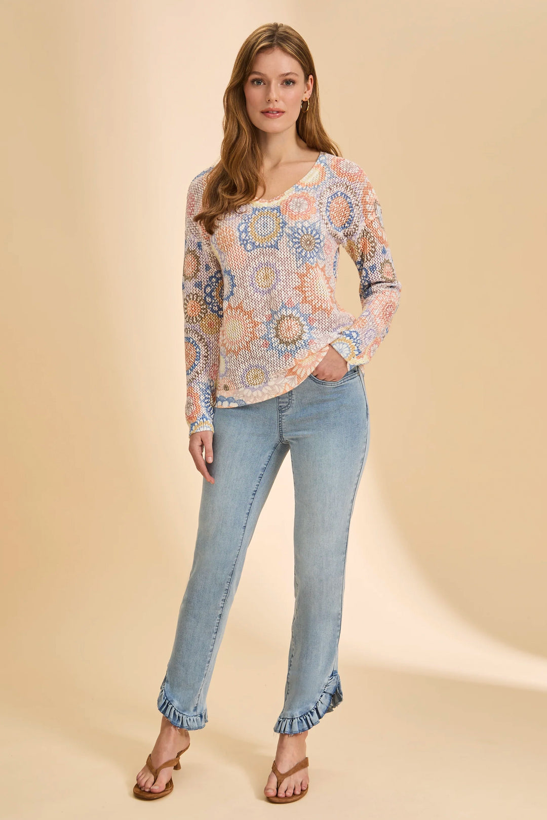 Woman wearing a patterned blouse and jeans on a beige background